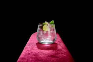 Siyah üzerine taze soğuk mojito, nane ve limon dilimi serpiştirilmiş eski moda cam.
