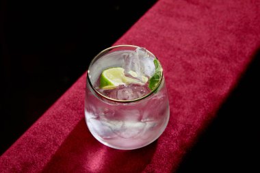 Yüksek açılı mojito manzaralı limon, nane ve buz küpleri eski moda camla siyah üzerine izole edilmiş.