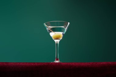 Düşük açılı kokteyl camı, vermut ve yeşil üzerine izole edilmiş kürdan zeytin.