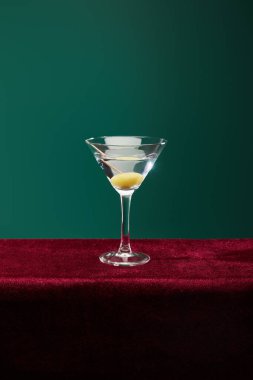Crystal cocktail glass with vermouth and whole olive on toothpick isolated on green clipart