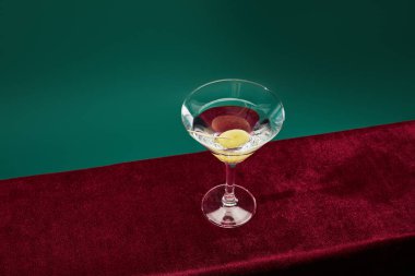 High angle view of cocktail glass with vermouth and whole olive on toothpick isolated on green  clipart