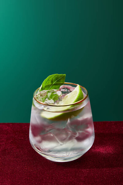 Close up view of old fashioned glass with golden rim with mojito isolated on green 