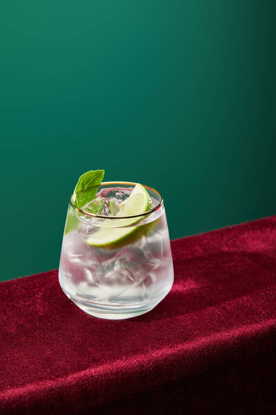 high angle view of mojito with mint and ice in glass isolated on green