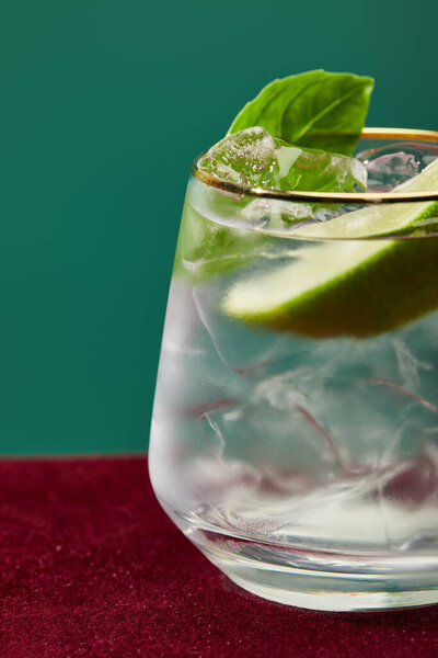 Close up view of refreshing mojito with mint in glass with golden rim isolated on green 