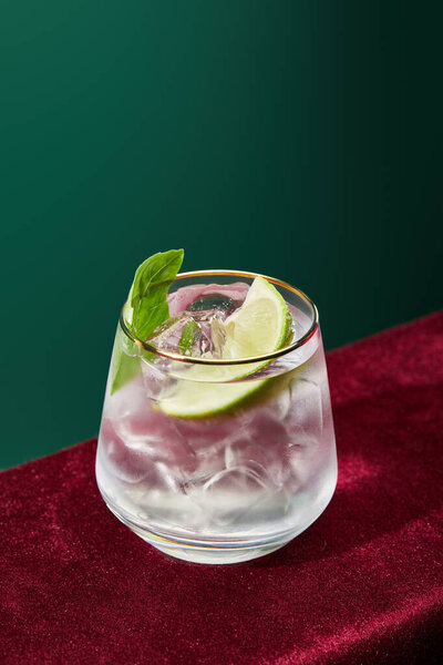 high angle view of refreshing mojito with mint and ice in glass with golden rim isolated on green 