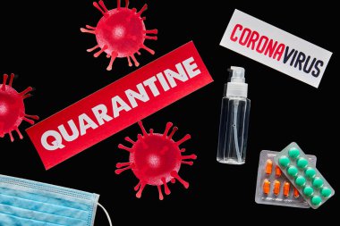 top view of papers with quarantine and coronavirus lettering near medical mask, pills and hand sanitizer isolated on black  clipart