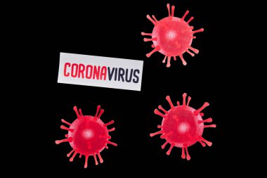 Siyah üzerine izole edilmiş virüsün yanına yazılmış koronavirüs harfli kağıdın üst görüntüsü 