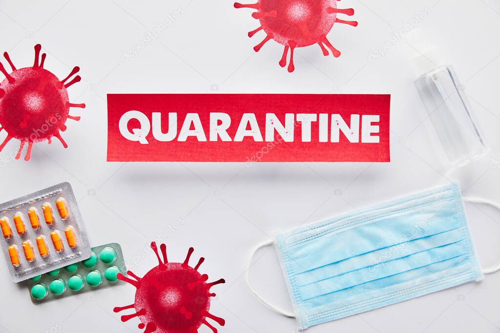 top view of paper with quarantine lettering near drawn virus, medical mask, pills and hand sanitizer on white 