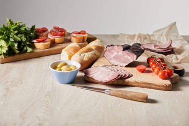 Tahtaya bıçak, maydanoz, kiraz domatesleri, kanepenin yanındaki zeytin ve baget eklenmiş lezzetli jambonun seçici odak noktası.