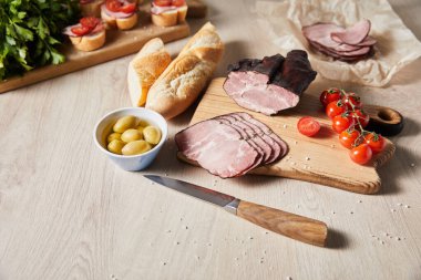 Tahtayı bıçakla, maydanozla, kirazlı domateslerle, zeytinlerle ve bagetlerle dilimlemenin seçici odak noktası.