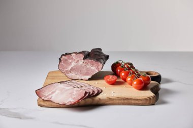 tasty ham on cutting board with salt and cherry tomatoes on white marble surface isolated on grey clipart