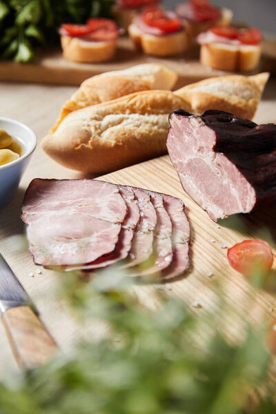 selective focus of tasty ham on cutting board with baguette