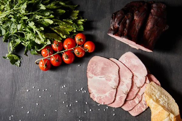 Top view of tasty ham sliced ham, cherry tomatoes, parsley, salt and baguette on wooden grey table — Stock Image Top View Tasty Ham Sliced Ham Cherry Tomatoes Parsley Salt Royalty Free Stock Images