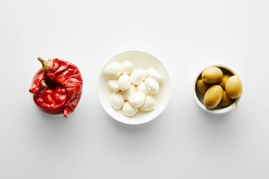 Zeytinli kase manzarası, marine edilmiş kırmızı biber ve beyaz arka planda mozzarella. 