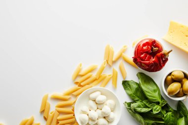 Makarna, fesleğen, zeytinli peynir ve kase, salamura biber ve beyaz arka planda mozzarella. 