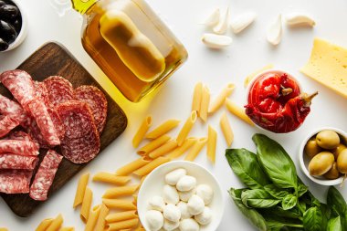 Makarna manzarası, bir şişe zeytinyağı, et tabağı ve beyaz arka plandaki malzemeler. 