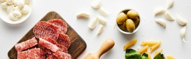 Beyaz arka planda et tabağı, merdane, makarna, sarımsak ve zeytin ve mozzarellanın panoramik oryantasyonu