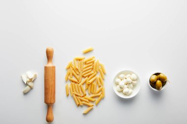 Sarımsak, merdane, makarna, zeytinli kaseler ve beyaz arka planda mozzarella ile yassı yatıyordu. 