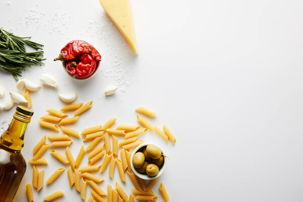 Top view of bottle of olive oil, pasta, cheese and ingredients on white background 