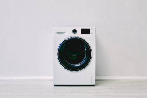modern washing machine near white wall in bathroom 