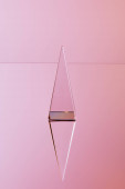 crystal transparent pyramid with reflection on pink background