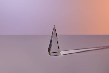 Gri arkaplanda ışık yansıması olan şeffaf kristal piramit