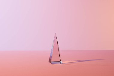 Pembe arkaplanda yansıması olan şeffaf kristal piramit