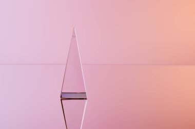 Pembe arkaplanda yansıması olan şeffaf kristal piramit