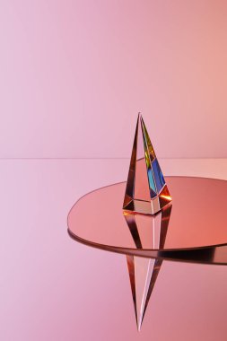 Pembe arka planda yuvarlak aynada yansıması olan kristal şeffaf piramit