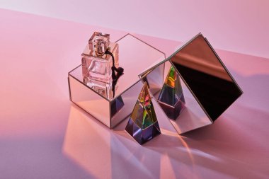 crystal transparent pyramid near perfume bottle and mirror cubes on pink background clipart