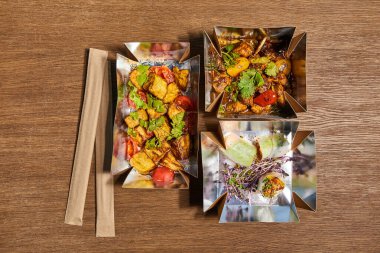 Yemek çubuklarının kağıt ambalajında üst görüntüsü hazır Çin yemekleri ve ahşap yüzey. 