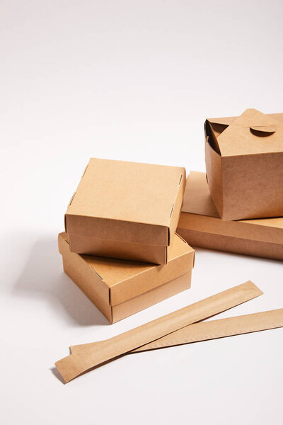 chopsticks in paper packaging near carton boxes with chinese food on white 
