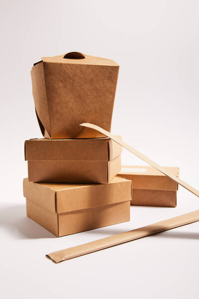 chopsticks in paper packaging near takeaway carton boxes with traditional chinese food on white 