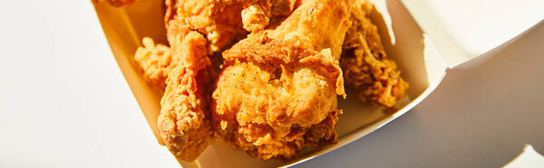 close up view of tasty deep fried chicken with chili pepper on white table in sunlight, panoramic crop