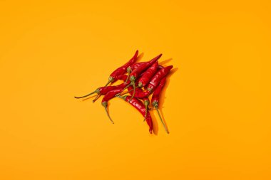 top view of red spicy chili peppers on orange colorful background clipart