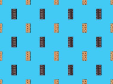 top view of sweet dark chocolate bars and crispbread on blue colorful background, seamless pattern clipart