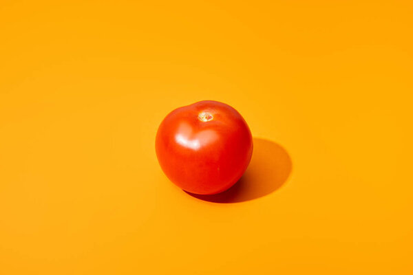 ripe fresh tomato on orange background