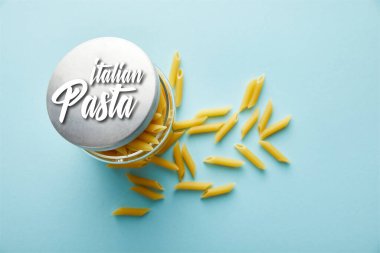 Üst görünüm çiğ makarna kavanozdan mavi arkaplana dağılmış İtalyan makarna illüstrasyonu ile