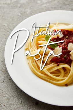 Gri desenli yüzeyde domates soslu leziz spagetti İtalyan makarna resimli.
