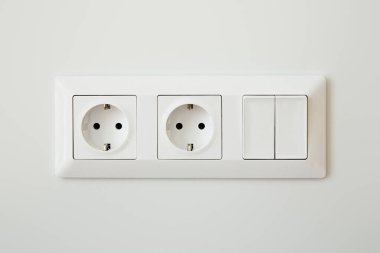 Elektrik prizleri beyaz duvardaki düğmeye yakın.