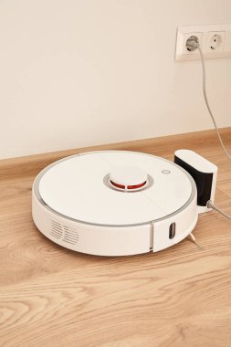 Duvardaki elektrik prizlerinin yakınındaki modern robotik süpürge. 