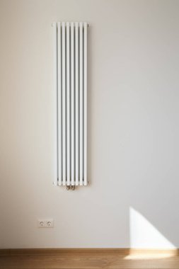 white and modern heating radiator near wall with power sockets  clipart