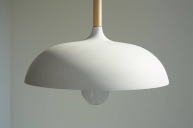 close up of white and modern lamp with light bulb near wall clipart