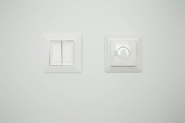 Beyaz duvarda düğmesi olan panelin yanında sıcaklık denetleyici