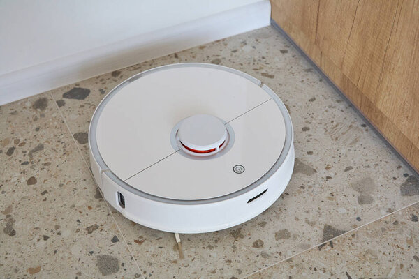 modern robotic vacuum cleaner washing floor tiles in apartment 