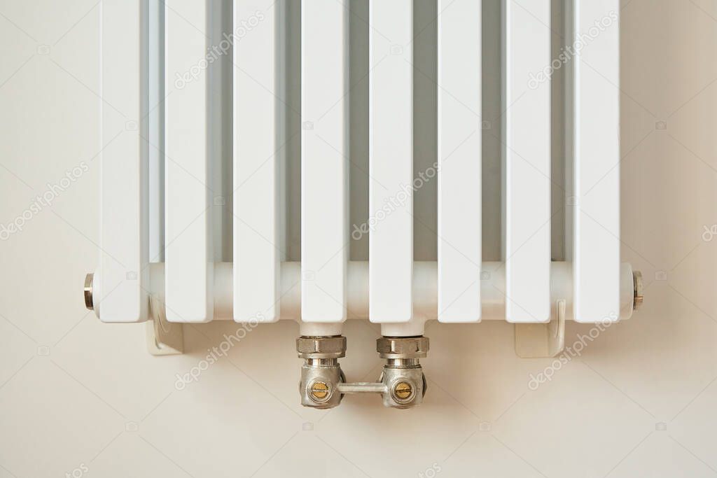 white and modern heating radiator near wall in apartment 