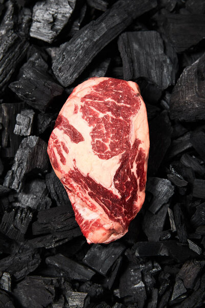 top view of fresh raw steak on black coals