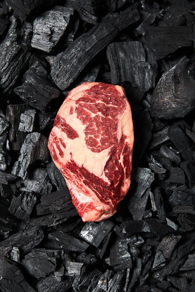 top view of fresh raw steak on black coals