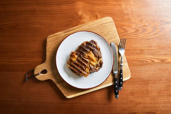 Felülnézet Friss Grillezett Steak Tányéron Vágódeszkán Evőeszközökkel Asztalon — Stock Fotó