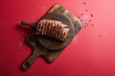 top view of tasty grilled steak served on wooden boards on red background with pepper and salt clipart